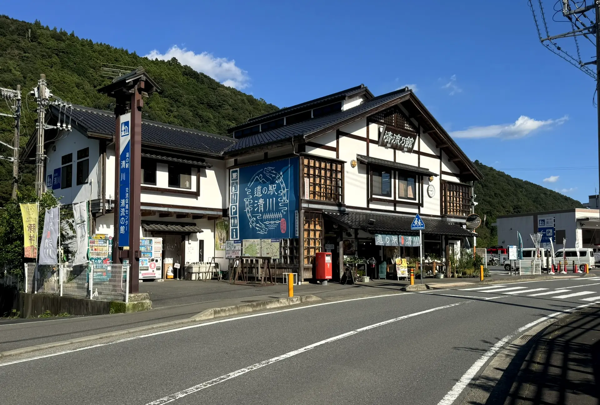 青空の下、木組みの白壁に「清流の館」の看板がかかる道の駅清川の正面(写真)